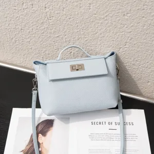 Detalle de bolso de cuero azul claro, asa superior clásica y diseño de cierre de giro.