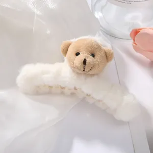 Closeup of a cute fluffy plush bear hair claw clip in white and tan, soft texture, detail view.