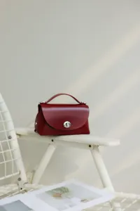 Detalle de bolso de hombro de cuero rojo vino, diseno retro vintage con cierre de giro.