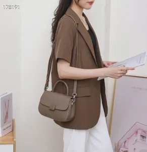 Detail shot of vintage brown leather crossbody bag with top handle and flap closure.