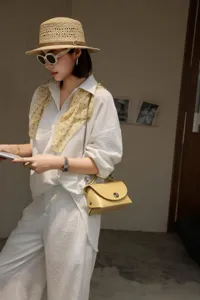 Bolso bandolera de sobre de cuero amarillo con cadena metálica y detalle de cierre.