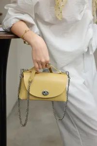 Bolso de hombro de cuero amarillo de moda con correa de cadena y cierre de giro elegante.
