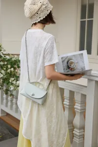 Elegante bolso cruzado de cuero verde claro con correa de cadena y cierre de giro ideal.