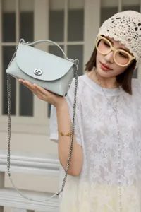 Elegante bolso bandolera de cuero azul claro con cadena y cierre de vuelta para mujer.