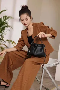 Elegante schwarze Leder Cloud Schultertasche mit Kordelzug Detail im Studio am Model präsentiert.