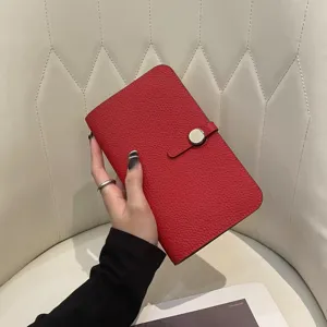 Red leather passport holder with metal snap closure, stylish travel wallet for women.