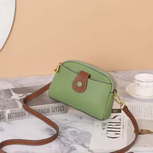 Detailed view of the green genuine leather crossbody bag featuring a brown buckle and slim strap.