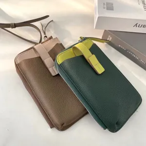 Dettaglio di piccole borse a tracolla per cellulare in vera pelle dai colori a contrasto.