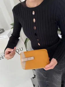 Dettaglio della borsa porta cellulare in pelle con design bicolore e zip elegante.