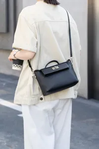 Bolso de mano de cuero negro con asa y cierre de giro para un estilo de vida elegante.