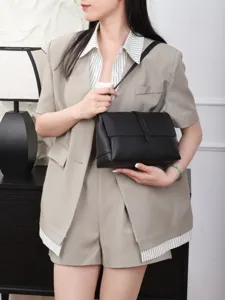 Detailed view of a stylish black leather shoulder bag with flap and vertical clasp.