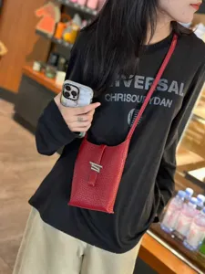 Vue détaillée d'un élégant mini sac bandoulière en cuir rouge porté par le modèle.