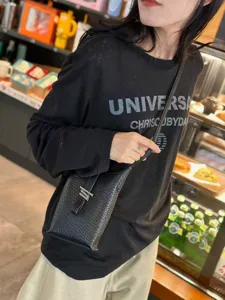 Sac bandoulière en cuir texturé noir pour femme, petit sac porté épaule élégant et pratique.