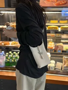 Vue détaillée du sac bandoulière texturé pour femme avec boucle métallique dans un café.