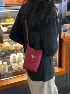 Détail de mini sac bandoulière en cuir texturé rouge, sac à épaule tendance pour le travail.