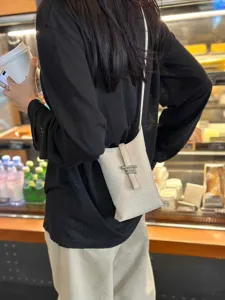 Sac bandoulière vertical minimaliste élégant pour femme, sac en cuir texturé de haute qualité.