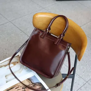 Dunkelbraune Vintage Handtasche aus echtem Leder mit Tragegriffen und verstellbarem Schultergurt.