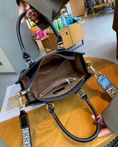 Schwarze Ledertasche mit Tragegriffen und gemustertem Schulterriemen für den Alltag.