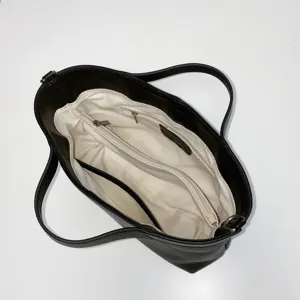 Detailed top view of the black leather tote bag interior, showing compartments and lining.