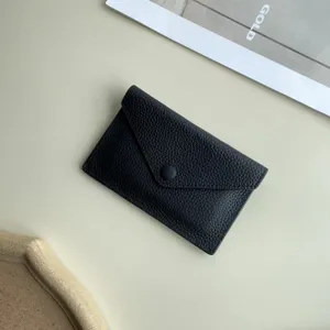 Gros plan detaille d un etui porte-cartes en cuir noir souple avec fermeture a bouton.