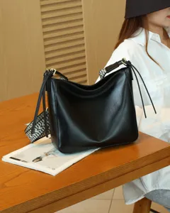 Classic black genuine leather women shoulder bag with wide strap and tassel detail for daily use.