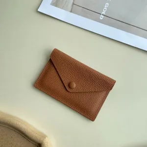 Gros plan sur le porte-cartes enveloppe en cuir veritable avec texture douce et bouton-pression.