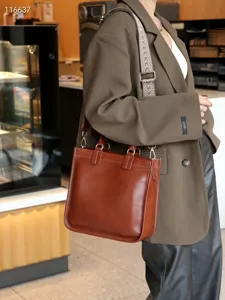Detailaufnahme der braunen Ledertasche mit stilvollem Musterriemen und feinen Kontrastnähten.
