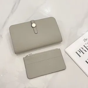 Detailed view of grey leather passport holder and matching card case on a white marble surface.
