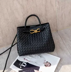 Primo piano dettagliato della borsa a secchiello nera intrecciata con dettagli dorati.