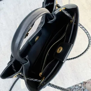 Vista dettagliata della borsa a mano intrecciata nera con dettagli dorati e scomparti interni.
