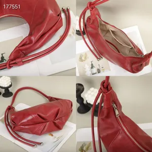 Detailed view of the red leather pleated underarm bag showing texture, strap and zipper.