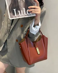 Vue détaillée d'un sac seau marron rétro avec boucle en métal, tenu par un mannequin.