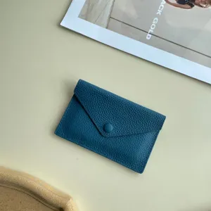 Détail de petit portefeuille enveloppe en cuir bleu, porte-cartes fin et élégant.