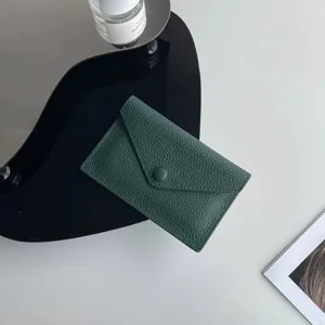 Détail d'étui de carte enveloppe en cuir vert foncé, mini portefeuille souple à bouton-pression.