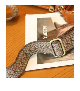Close-up detail of the vintage woven bag strap with multicolor pattern and brass hardware.