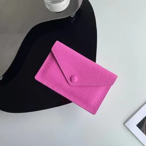 Gros plan détail du porte-monnaie enveloppe en cuir rose, design minimaliste élégant.