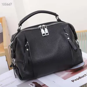 Black genuine leather top-handle shoulder bag close-up showing pebbled texture and zippers