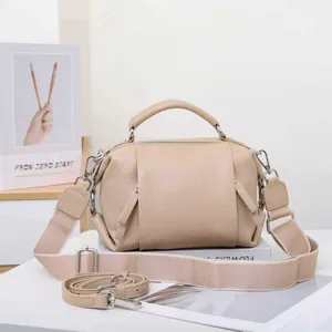 Detailed view of women genuine leather handbag, featuring top handle and wide crossbody strap.