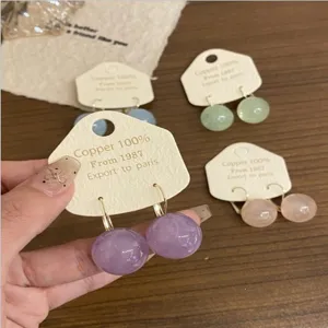 Gros plan de boucles d'oreilles rondes perles colorées avec étiquettes sur table en bois.
