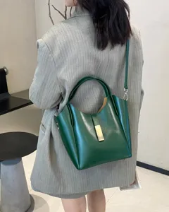Détail de sac seau en cuir vert, sac à épaule minimaliste avec fermoir métallique.