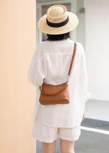 Detail view of brown leather crossbody shoulder bag worn by model, premium commuter style.