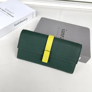 Dettaglio ravvicinato di portafoglio lungo donna verde scuro con cinturino giallo a contrasto.