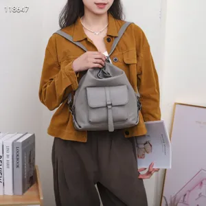 Sac à dos en cuir véritable gris en détail, montrant texture premium, poche avant et sangles.