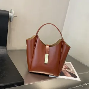 Gros plan détaillé du sac seau élégant en cuir marron avec une fermeture métallique chic.