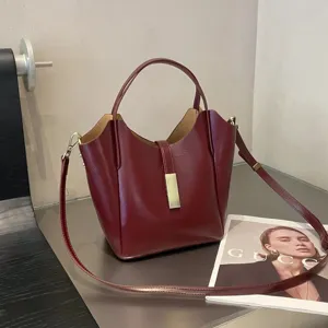 Vue détaillée de l'élégant sac seau rouge vin avec boucle et bandoulière en métal doré.
