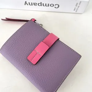 Detailed view of the purple and pink leather wallet showing fine stitching and metal zipper.