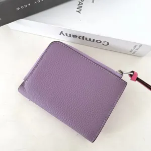 Close-up detail of genuine cowhide short women wallet in purple with color-contrast zipper pull.