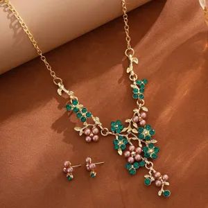 Detailed view of exquisite gold-toned pearl and green rhinestone flower necklace earrings set.