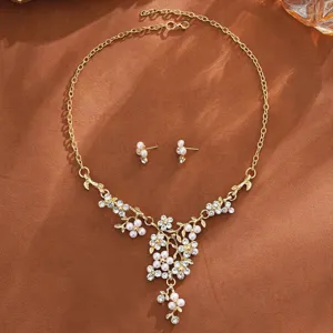Close-up detail of the elegant gold pearl flower necklace and earrings set on textured backdrop.
