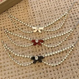 Detailaufnahme von mehrlagigen Strass-Choker-Halsketten mit niedlichen Schleifen-Akzenten.
